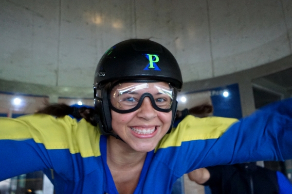 woman grins ear to ear indoor skydiving