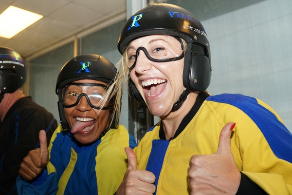 two women giving thumbs up after indoor skydive