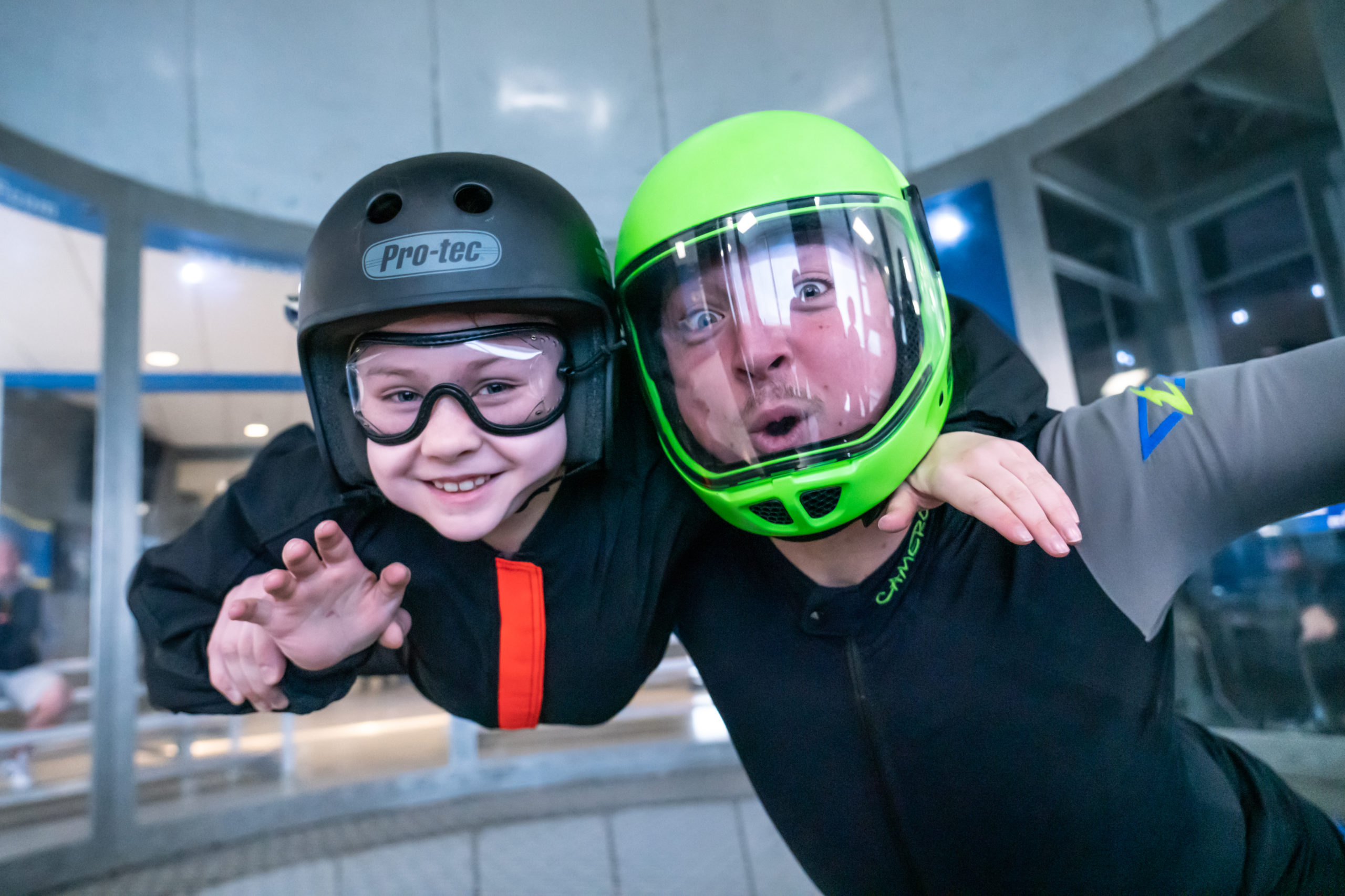 Child and instructor smile in the wind tunnel.