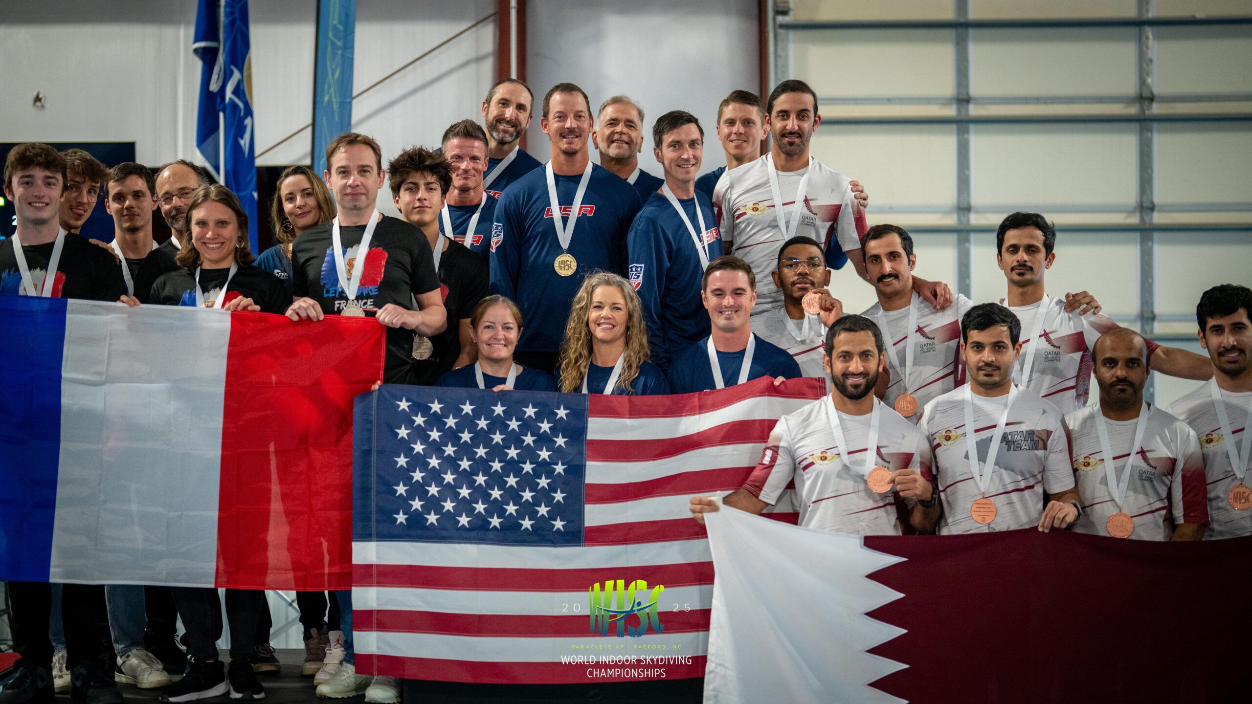 World indoor skydiving competitors on podium holding their nation's flags 